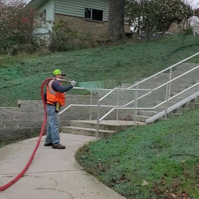 Worker using leaf blower on stairs outdoors near a house.