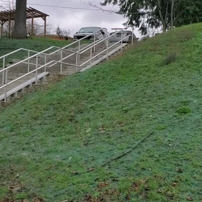 Outdoor staircase on grassy hill with parked cars at the top.