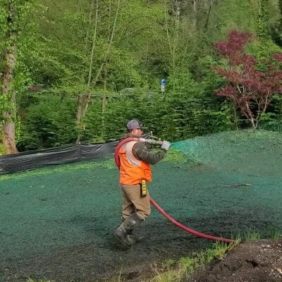 Worker applying hydroseed mixture on lawn in Washington State.