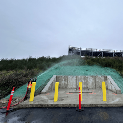 Hydroseeding process on sloped terrain with equipment and safety barriers.