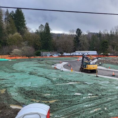 Construction site with excavators and backhoe on overcast day.