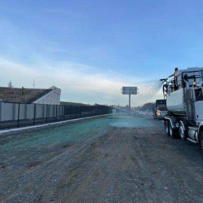 Semi truck spraying water on construction site road at dusk.