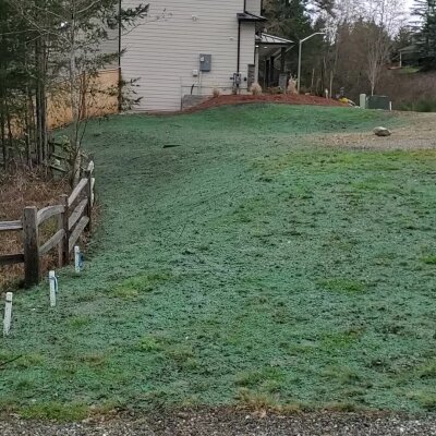 Grassy hillside with fence and building in background.