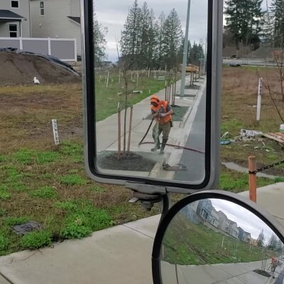 Worker with rake reflected in vehicle