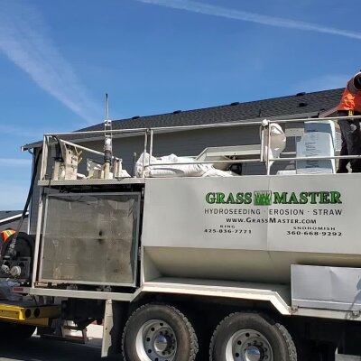 Hydroseeding truck with workers and equipment against a blue sky.