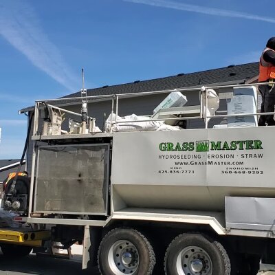 Hydroseeding truck with workers and equipment outside residential home.