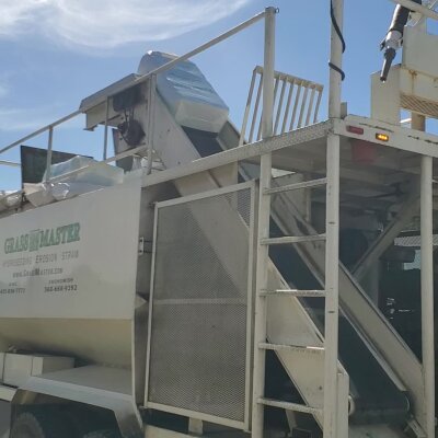 Industrial straw blower machine on a sunny day.