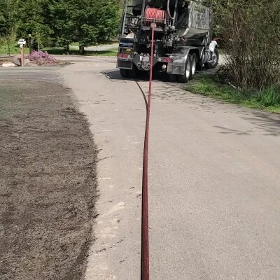 Garbage truck and worker on a sunny residential street.