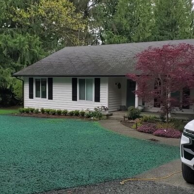 Single-story house with green lawn, red tree, and partial view of a vehicle.