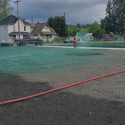 Hydroseeding process on lawn by worker in residential area.