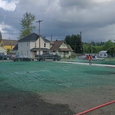 Hydroseeding process on a lawn with houses in the background.