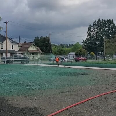 "Worker applying hydroseed mix to a new lawn in a residential area."