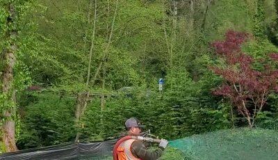 Worker applying hydroseed mixture on lawn in Washington State.