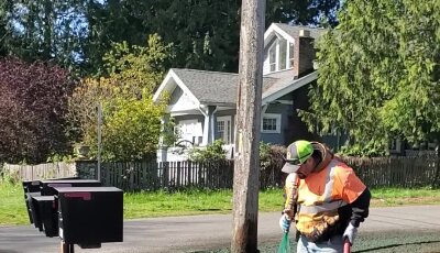 Worker applying hydroseed mixture to residential lawn in Washington State.