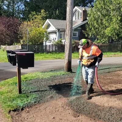 Worker applying hydroseed mixture to residential lawn in Washington State.