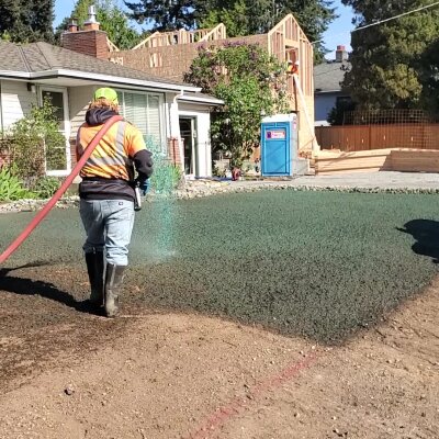 Worker applying hydroseed mixture to residential lawn in Washington state.