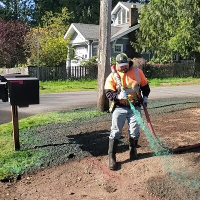 Worker applying hydroseed mixture on Washington state lawn.