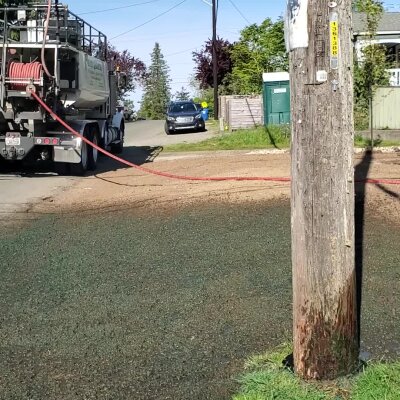 Hydroseeding truck spraying grass seed on residential lawn in Washington State.
