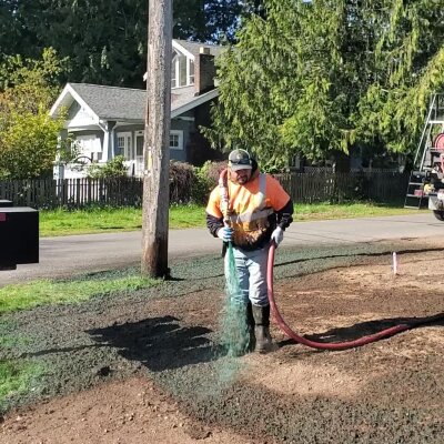 Worker applying hydroseed mixture on lawn in Washington state