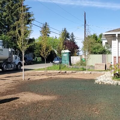 Hydroseeding lawn process with truck and hoses in residential area.