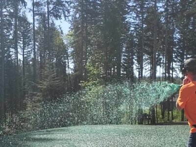 Worker hydroseeding a lawn with equipment in Washington state.