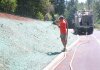 Worker applying hydroseed mixture from truck on sloped terrain.